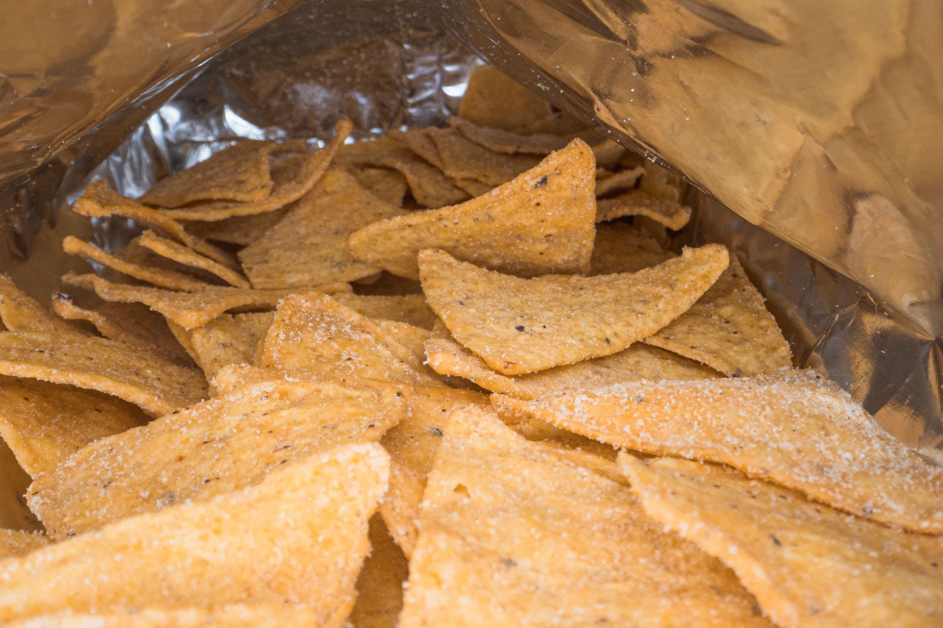 Detailed image of crispy salted corn chips inside an open snack bag.